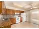 Traditional kitchen boasts wooden cabinetry, granite countertops, white appliances, and a sliding glass door at 440 S Parkcrest -- # 145, Mesa, AZ 85206