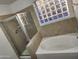 Bathroom featuring a glass-enclosed shower, soaking tub, and natural light from the glass-block window at 4534 E Villa Maria Dr, Phoenix, AZ 85032
