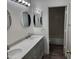 Bathroom featuring double sink vanity, marble counters, round mirrors, and access to the shower at 4534 E Villa Maria Dr, Phoenix, AZ 85032