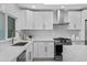 Kitchen features a gas range, stainless steel hood, subway tile backsplash, and white cabinets with gold hardware at 8732 E Arlington Rd, Scottsdale, AZ 85250
