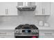 Stainless steel gas range with a modern vent hood and tile backsplash create a chef's dream kitchen at 8732 E Arlington Rd, Scottsdale, AZ 85250