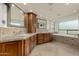 Luxurious bathroom featuring granite countertops, dual sinks, wood cabinetry, and a large soaking tub by a window at 10105 E Larkspur Dr, Scottsdale, AZ 85260
