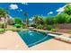 Backyard pool with diving board, surrounded by lush landscaping, grass and lounge seating at 10105 E Larkspur Dr, Scottsdale, AZ 85260