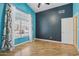 Bright bedroom with a large window, light hardwood floors, and stylish blue and dark blue accent walls at 12183 E Mercer Ln, Scottsdale, AZ 85259