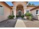 Charming front entry with large columns, arched entrance, and decorative desert landscaping at 12183 E Mercer Ln, Scottsdale, AZ 85259