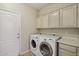 Laundry room with white cabinets, tile floors, and modern washer and dryer at 12183 E Mercer Ln, Scottsdale, AZ 85259