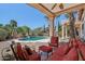 Comfortable covered patio with red-striped furniture overlooking the sparkling pool and lush landscaping at 12183 E Mercer Ln, Scottsdale, AZ 85259