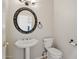 Powder room with pedestal sink, oval mirror, and toilet at 12183 E Mercer Ln, Scottsdale, AZ 85259