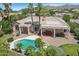 Gorgeous aerial of desert home featuring a private swimming pool, covered patio, and mountain views in a lush, gated community at 12183 E Mercer Ln, Scottsdale, AZ 85259