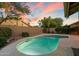 A shimmering pool under the evening sky surrounded by a brick fence and mature trees at 13361 N 99Th Pl, Scottsdale, AZ 85260