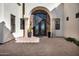 Elegant arched front door with decorative ironwork, complemented by stone pillars and manicured landscaping at 13648 E Aloe Vera Dr, Scottsdale, AZ 85262