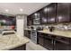 Elegant kitchen with stone backsplash, granite counters, and dark cabinetry featuring modern appliances at 16105 N 183Rd Dr, Surprise, AZ 85388