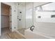 Bright bathroom featuring a soaking tub, glass shower, wood-look floors, and a walk-in closet at 1903 E Empeltre Rd, San Tan Valley, AZ 85140