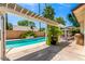 Backyard pool area with a pergola, large potted plants, and a lush green surroundings for a relaxing outdoor experience at 2230 N Los Alamos --, Mesa, AZ 85213
