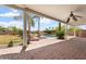 Expansive backyard patio with brick pavers and a covered area, leading to lush landscaping and a beautiful pool at 22737 N Sunset Dr, Maricopa, AZ 85139