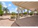Expansive backyard patio with brick pavers and a covered area, leading to lush landscaping and a beautiful pool at 22737 N Sunset Dr, Maricopa, AZ 85139