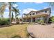 Expansive backyard with a covered patio, lush lawn, mature trees, and a brick-paved patio at 22737 N Sunset Dr, Maricopa, AZ 85139
