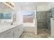 Bright bathroom featuring a shower, tub, and large window at 22737 N Sunset Dr, Maricopa, AZ 85139