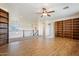 Bright open room features hardwood floors, high ceilings, a fan, and beautiful built-in bookshelves at 22737 N Sunset Dr, Maricopa, AZ 85139