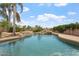 Beautiful pool featuring rock waterfall, spa, and lush landscaping with palm trees under sunny blue skies at 22737 N Sunset Dr, Maricopa, AZ 85139