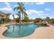 Beautiful pool featuring rock waterfall, spa, and lush landscaping with palm trees under sunny blue skies at 22737 N Sunset Dr, Maricopa, AZ 85139