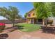 A Backyard with green grass, rocks, and trees, with a view of the second story at 24813 W Rosita Ave, Buckeye, AZ 85326