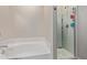 Bathroom featuring a tub and separate glass-enclosed shower, with neutral tiling at 25447 W Heathermoor Dr, Buckeye, AZ 85326
