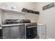 Efficient laundry room with modern washer and dryer, floating shelves, and ample space for storage and organization at 25447 W Heathermoor Dr, Buckeye, AZ 85326