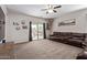 Spacious living room featuring a sliding glass door to the backyard and a large leather sofa at 25447 W Heathermoor Dr, Buckeye, AZ 85326