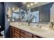 Bathroom featuring double sinks, dark blue walls, white countertop and a large mirror with vanity lighting at 25930 N 165Th Ln, Surprise, AZ 85387