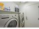 Bright laundry room with a door and gray front loading washer and dryer at 25930 N 165Th Ln, Surprise, AZ 85387