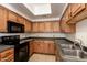 Kitchen featuring wood cabinets, a stainless steel sink, and black appliances at 3434 E Baseline Rd # 216, Phoenix, AZ 85042