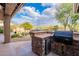 A built-in outdoor kitchen features a stone base, tile counters, grill and beverage fridge at 5077 E Lonesome Trl, Cave Creek, AZ 85331