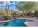 Lush backyard with a sparkling pool, rock waterfall feature, and plenty of greenery, all enclosed by a fence at 5077 E Lonesome Trl, Cave Creek, AZ 85331