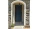 Close-up of the front door, featuring stone accents, an overhead light, and house numbers at 6614 W Polk St, Phoenix, AZ 85043