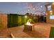 Beautiful backyard at twilight with fire pit, string lights, and lush privacy landscaping at 6632 W Saguaro Park Ln, Glendale, AZ 85310
