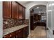 Butlers pantry with granite countertops, tiled backsplash, and dark wood cabinetry at 6632 W Saguaro Park Ln, Glendale, AZ 85310