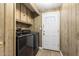 Laundry room featuring new black appliances, storage cabinets, and a white entry door at 9501 E Broadway Rd # Ofc, Mesa, AZ 85208