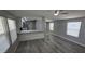 Open living space with gray plank floors, two windows, recessed lights, and kitchen with breakfast bar at 9632 E Arbor Cir, Mesa, AZ 85208
