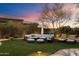 Lush backyard with comfortable seating and landscape lighting at dusk at 9675 E Roadrunner Dr, Scottsdale, AZ 85262