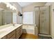 Bright bathroom featuring a double vanity, soaking tub, and a glass-enclosed shower at 1072 W Windhaven Ave, Gilbert, AZ 85233