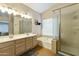 Bathroom featuring double sinks, soaking tub, and a glass-enclosed shower at 1072 W Windhaven Ave, Gilbert, AZ 85233