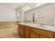 Bright bathroom with double sinks, wood cabinets, a large mirror and soaking tub at 10940 E Olla Ave, Mesa, AZ 85212