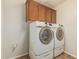 Practical laundry room with front loading washer and dryer and overhead cabinets at 10940 E Olla Ave, Mesa, AZ 85212