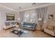 Bright living room featuring a velvet sofa, two armchairs, a glass coffee table, and neutral-toned walls at 1128 E Phelps St, Gilbert, AZ 85295