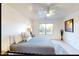 Bright bedroom with a ceiling fan, gray bedding, and a large window view at 13280 W Caribbean Ln, Surprise, AZ 85379