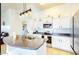 Bright kitchen with white cabinetry, stainless steel appliances, pendant lighting, and eat-in counter at 13280 W Caribbean Ln, Surprise, AZ 85379