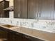 Modern kitchen features brown cabinetry, stylish countertops, and unique white and gray tile backsplash at 16035 W Questa Dr, Surprise, AZ 85387