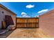 The backyard features a gate leading to a potential parking area, secured by a brick wall and a wooden fence at 16221 W Prickly Pear Trl, Surprise, AZ 85387