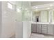 Clean bathroom with double sinks, gray cabinetry, and a modern shower with a glass enclosure at 16221 W Prickly Pear Trl, Surprise, AZ 85387